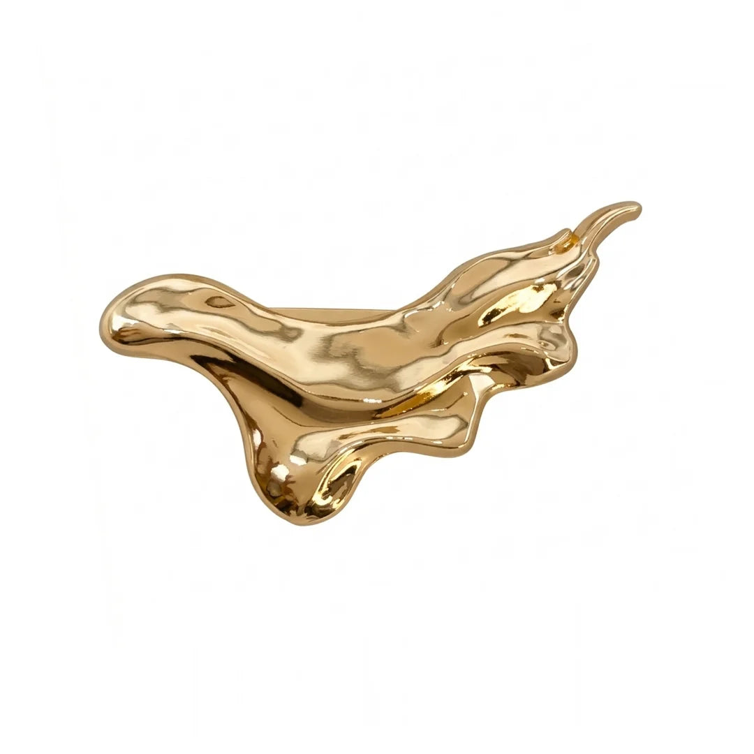 A polished gold abstract sculptural pin or brooch with a fluid, liquid-like organic shape, shown on a plain white background.