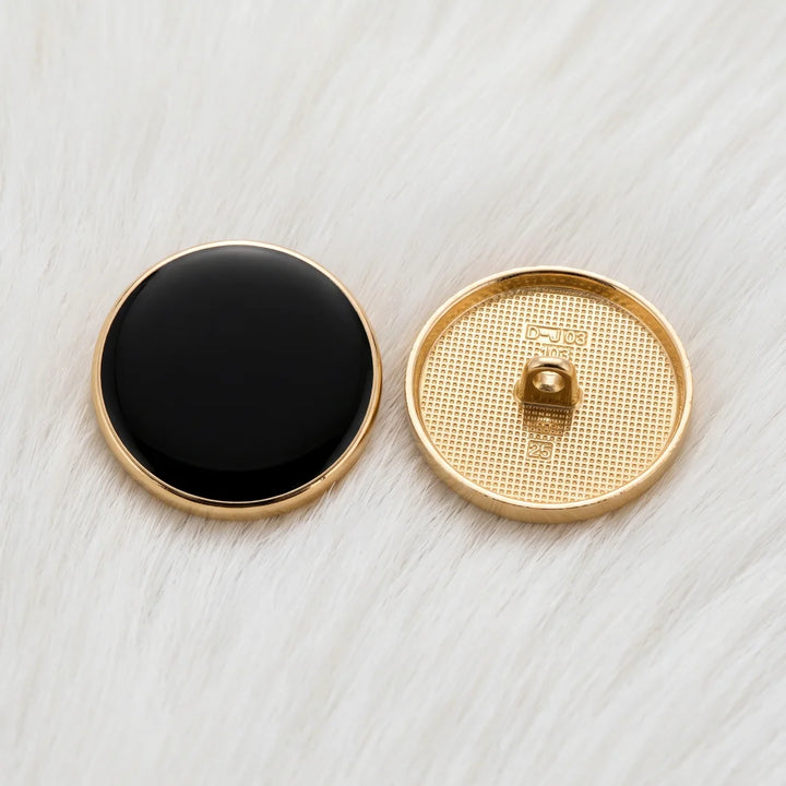 Black resin gold rim metal shank button shown front and back, with textured gold back and shank, on white fur background