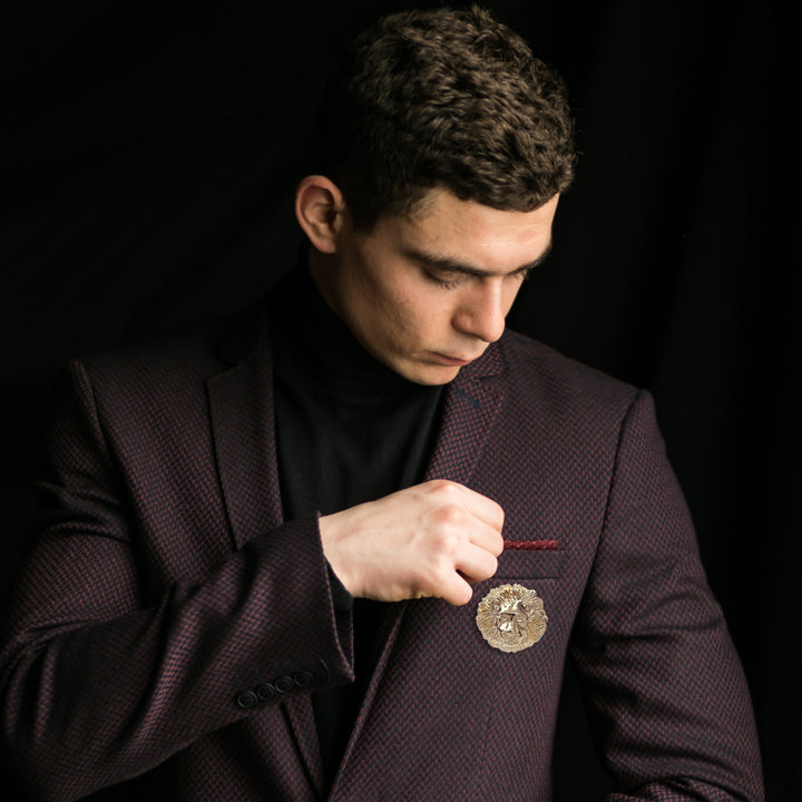 Ani Accessories Lion Head Metal Gold Buckle placing on the pocket of the suit wearing by a male model in a dark background.