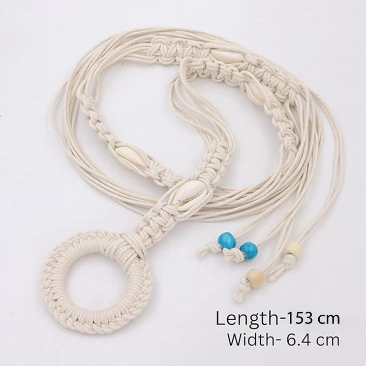 Ani Accessories Womens Belt Beige macrame belt with cowrie shells, styled over a gray dress. The belt threads through a large woven ring and hangs down.