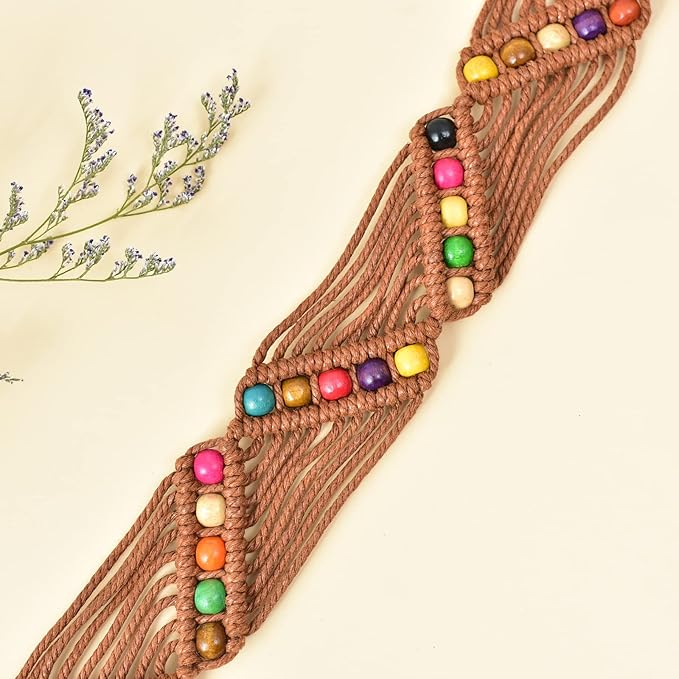 Ani Accessories Womens Belt Close-up detail of a brown macrame belt, showing rows of brightly colored round wooden beads (including red, orange, yellow, and green) woven into the knotted cord on a light background with dried florals in the upper left corner.