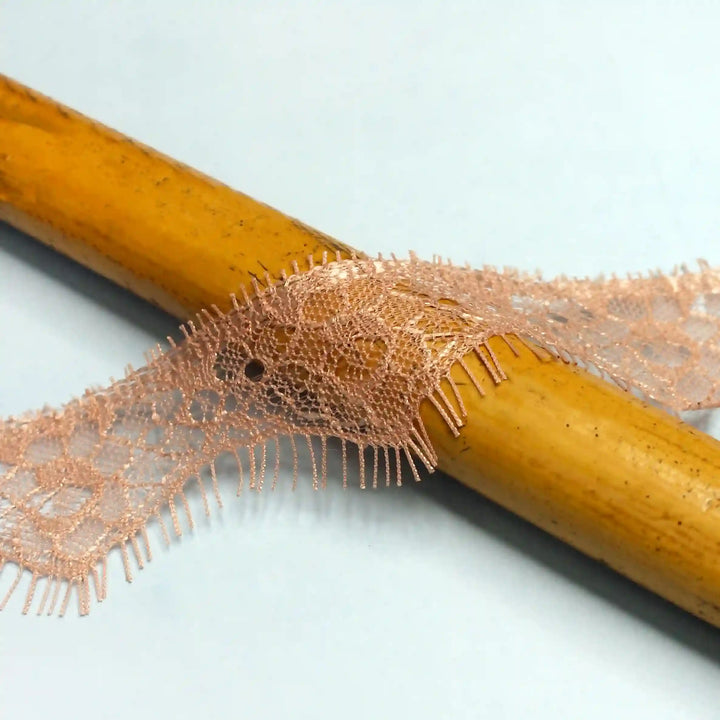 Buy now Peach Eyelash Trim Lace Fabric by Ani Accessories on a wooden surface showcasing its delicate texture