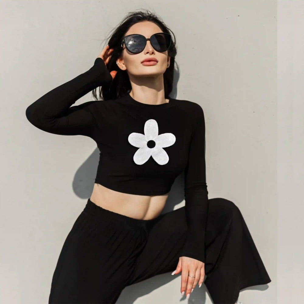 ANI Accessories big white daisy patch on a black crop top worn by a seated model 