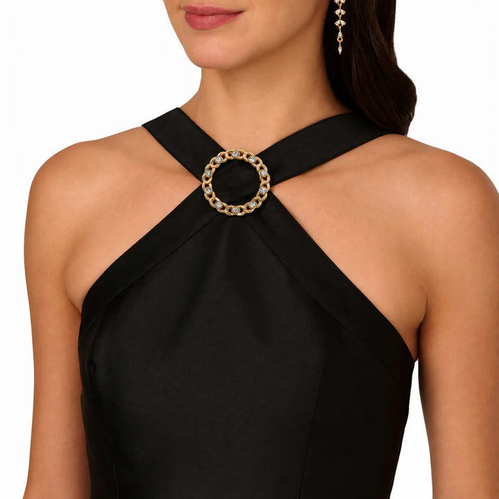 ANI Accessories round gold chain link rhinestone buckle used as a neckline accent on a black halter-neck dress