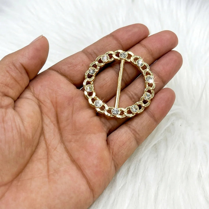 ANI Accessories round gold chain link rhinestone belt buckle held in palm to show real size, on white fur background