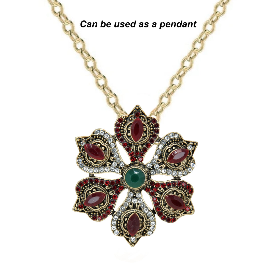 ANI Accessories antique gold flower brooch from an angle showing the raised red and green stones with white color background 