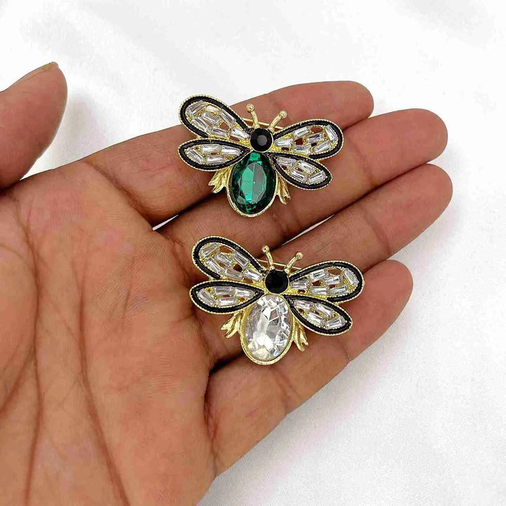 Two crystal bee brooches held in hand to show their size with white color background