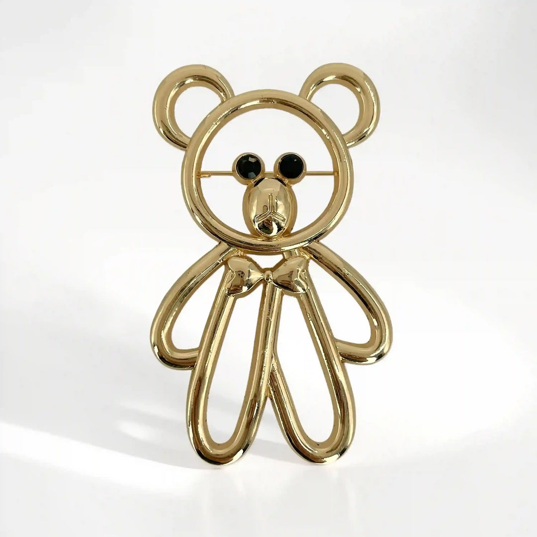 ANI Accessories cute teddy bear brooch in polished gold with black crystal eyes and a bow tie with white color background 