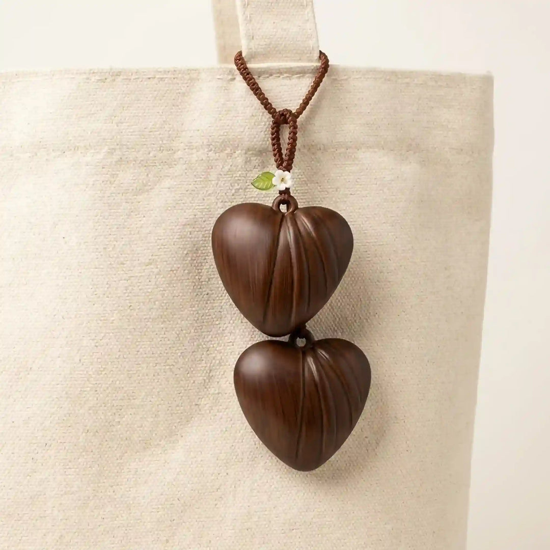 ANI Accessories two dark brown fluted heart charms hanging from a cord as a bag charm on a beige canvas tote bag 
with white color background 
