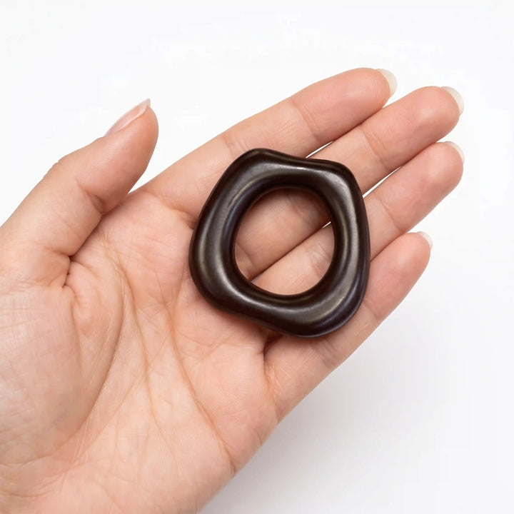 ANI Accessories dark brown organic ring pendant charm resting in an open palm to show real size, on white background