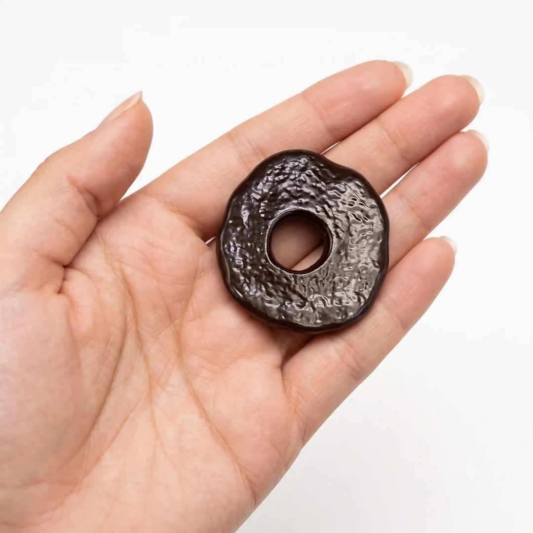 ANI Accessories dark brown textured donut pendant charm resting in an open palm to show real size, on white background