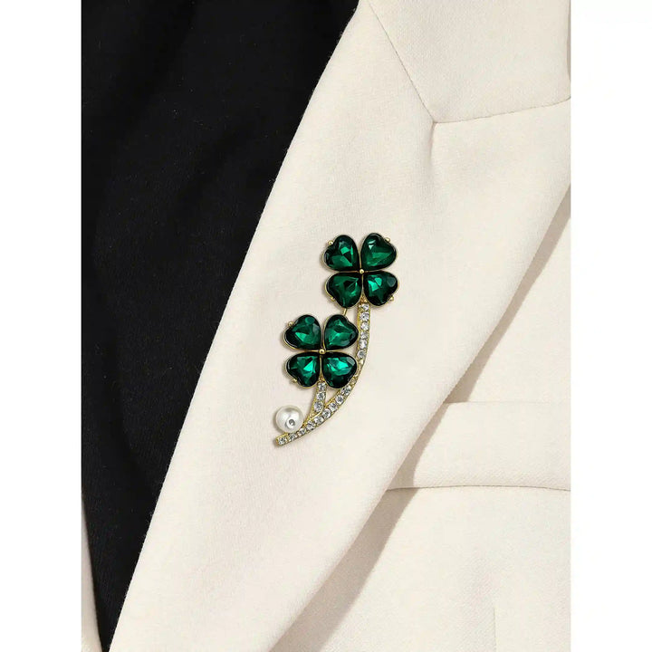 ANI Accessories emerald clover brooch pinned on the lapel of a white blazer 
