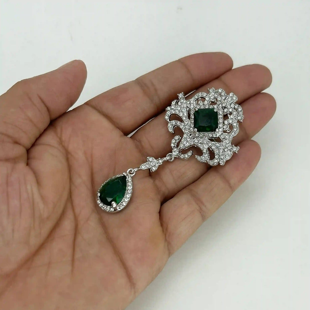 ANI Accessories emerald dangle brooch held in hand to show its size 