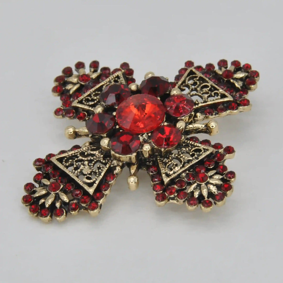 ANI Accessories filigree cross brooch from an angle showing the raised red centre stone 
