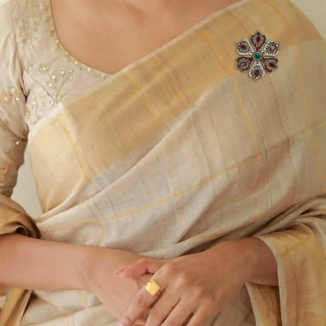 ANI Accessories flower corsage brooch on the shoulder of a cream and gold sareeb with white color background 