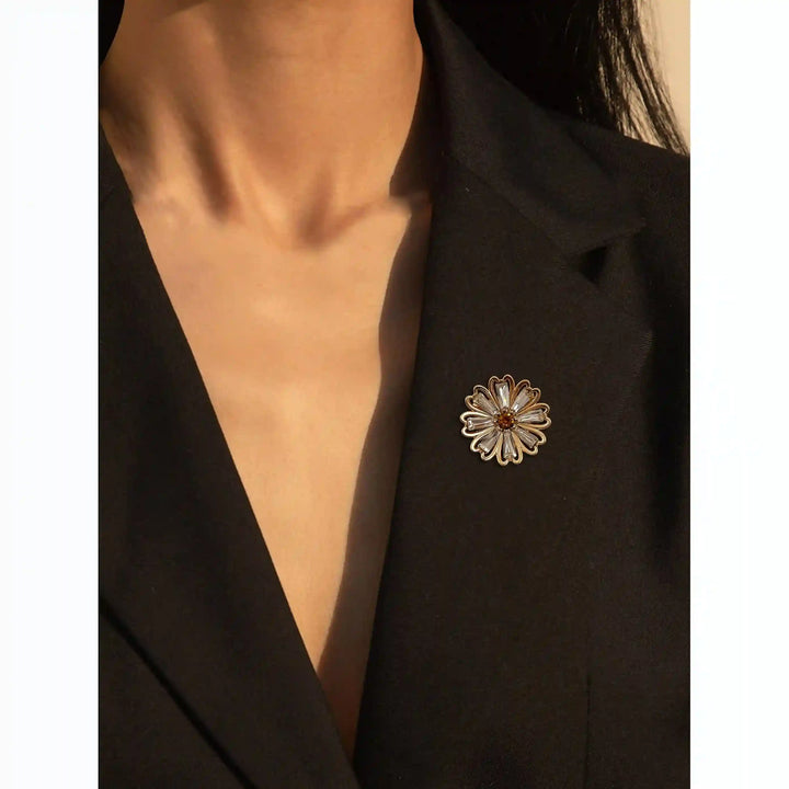 ANI Accessories gold daisy brooch pinned on a woman's black blazer with white color background 