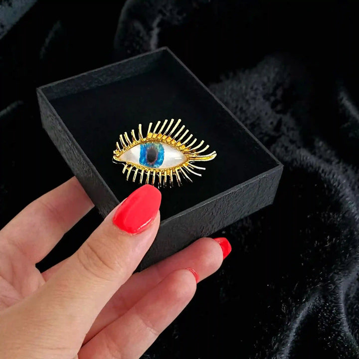 ANI Accessories gold evil eye brooch in a black box held in hand 