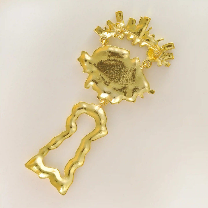 Back side of the gold eye brooch showing the brooch pin with white color background 