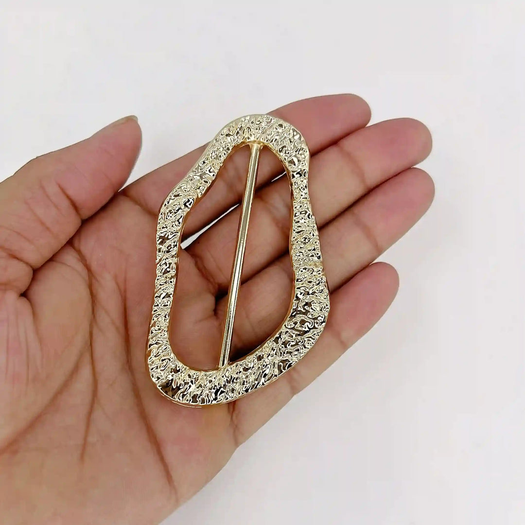 ANI Accessories gold hammered freeform slide buckle resting on an open palm to show its size
