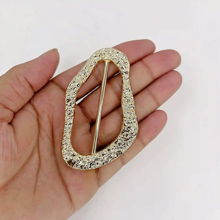 ANI Accessories gold hammered freeform slide buckle resting on an open palm to show its size