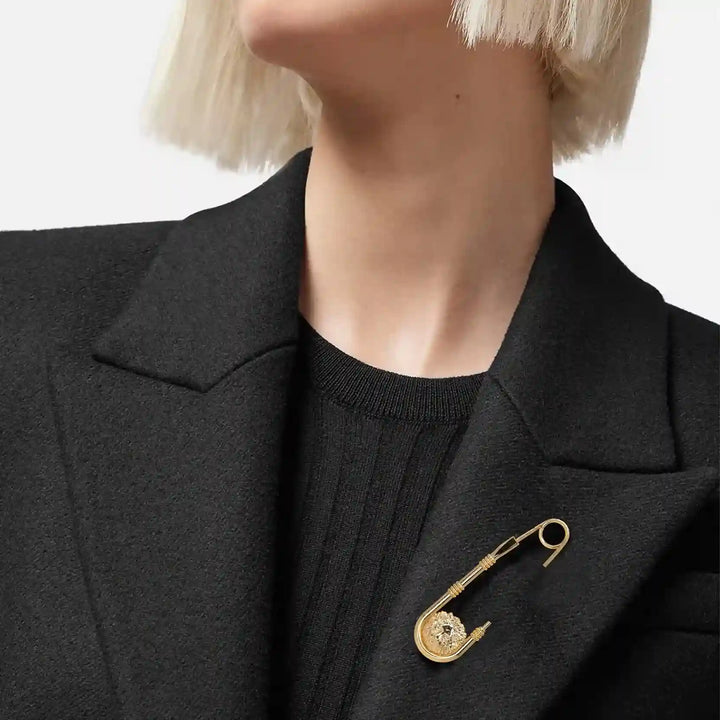 Woman wearing a gold lion head safety pin brooch on a black blazer lapel 