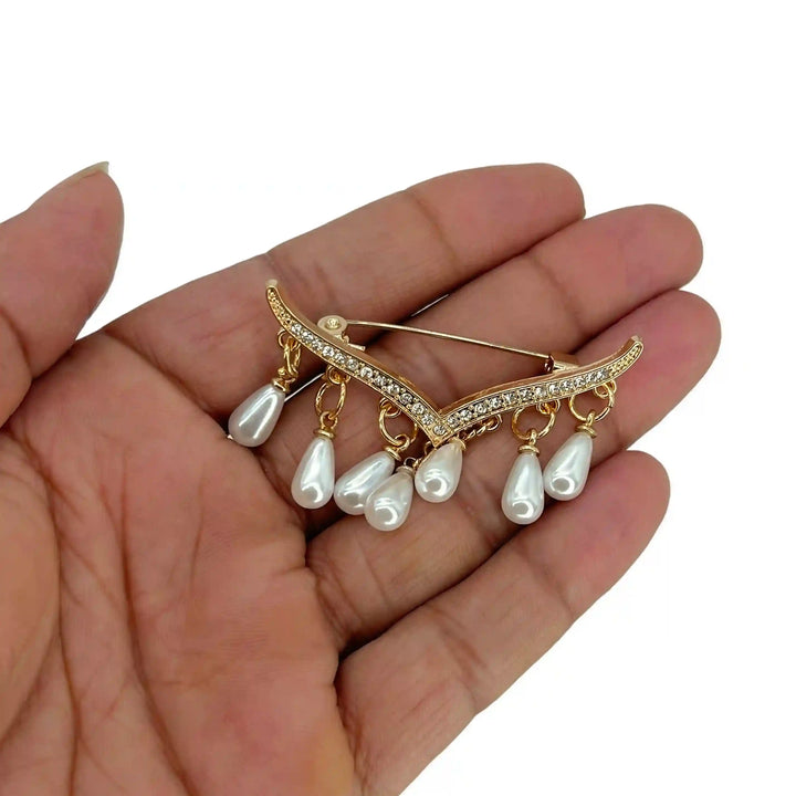 ANI Accessories gold V-shape pearl brooch held in hand to show its size with white color background 