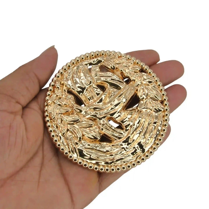 ANI Accessories large round gold brooch held in hand to show its big size with white color background 