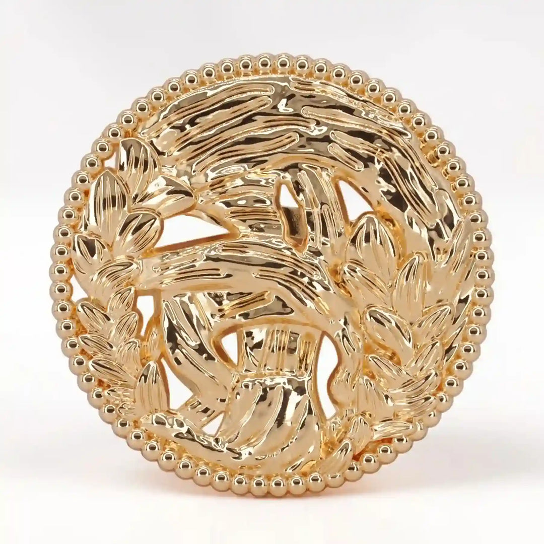 ANI Accessories large round gold brooch with swirling openwork and a beaded border, on white color background 