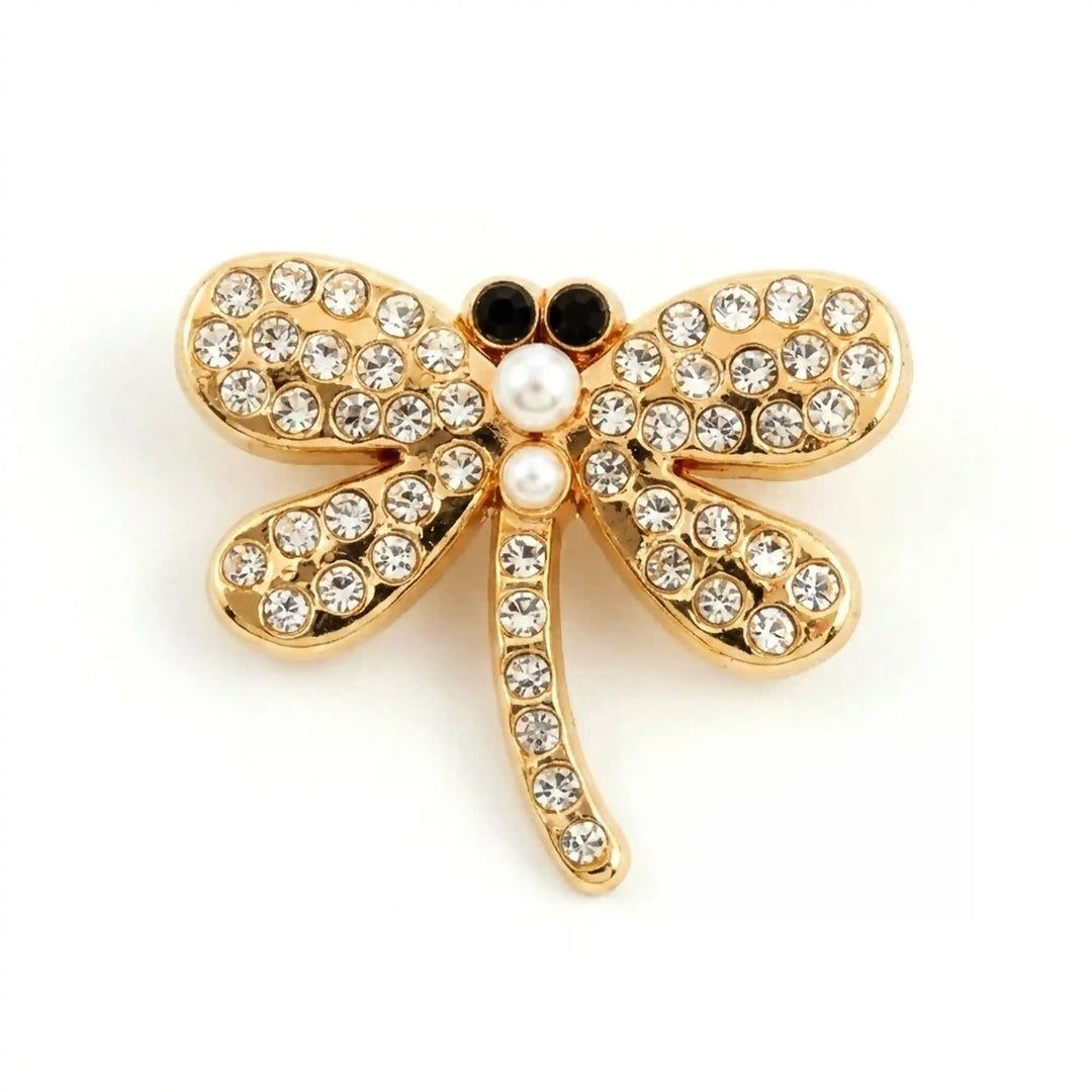 Mini gold dragonfly brooch with rhinestone wings, two pearls and black stone eyes with white color background 