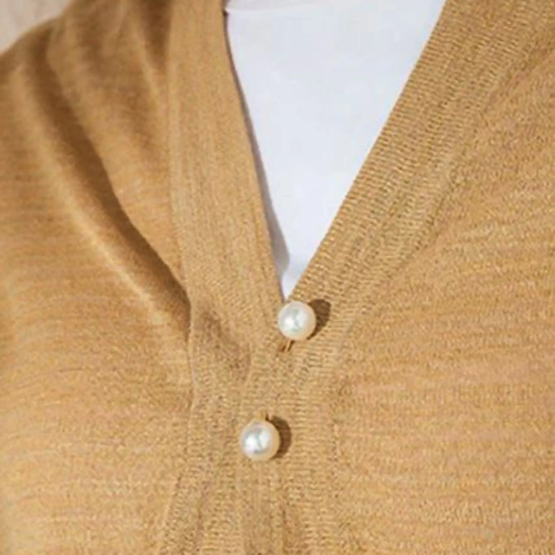 Twin pearl pin used to close the V-neck of a mustard cardigan 