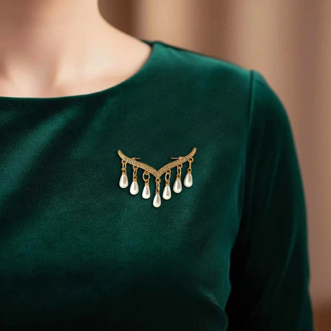 ANI Accessories gold pearl drop brooch pinned on the chest of a dark green top 