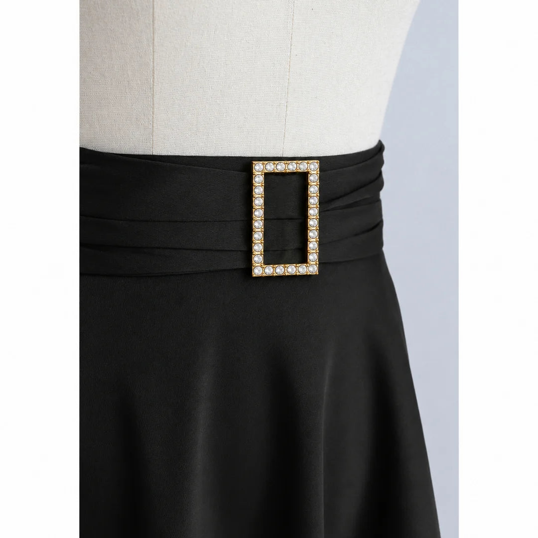 ANI Accessories rectangular studded gold buckle styled on the pleated waistband of a black flared skirt on a dress form Gray Background 