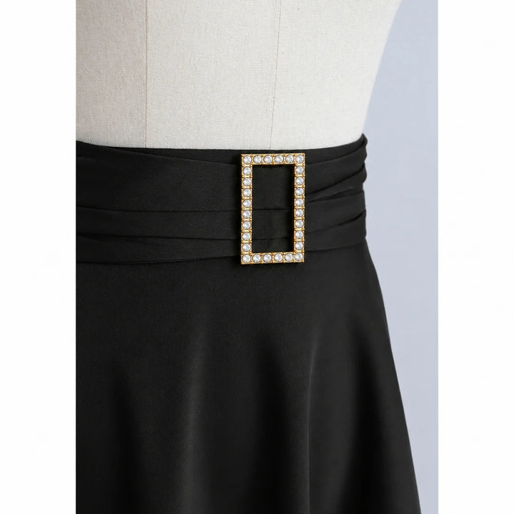 ANI Accessories rectangular studded gold buckle styled on the pleated waistband of a black flared skirt on a dress form Gray Background 