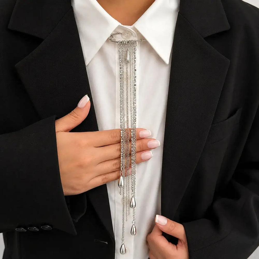 ANI Accessories silver chain tassel brooch worn at a white shirt collar under a black blazer 