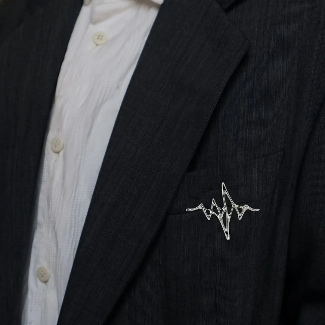 ANI Accessories silver wave brooch pinned on the lapel of a black blazer 