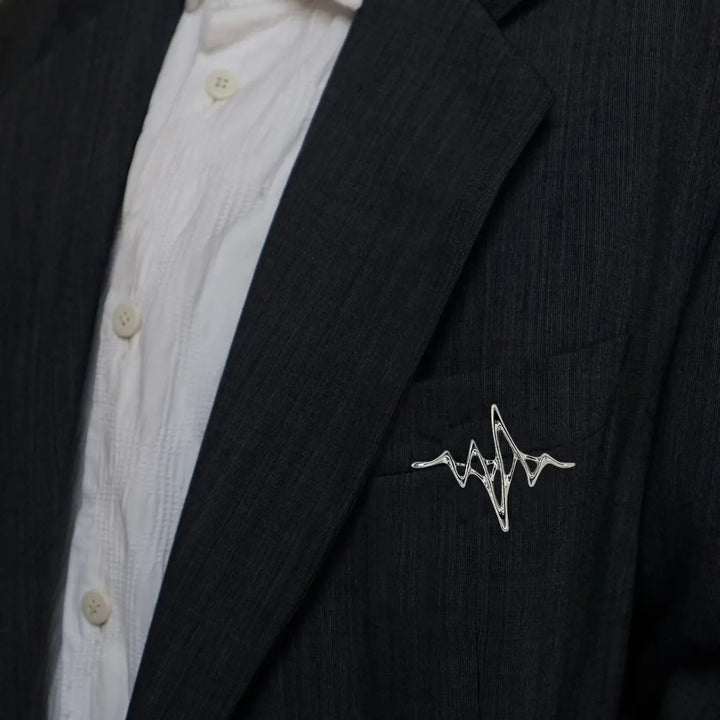 ANI Accessories silver wave brooch pinned on the lapel of a black blazer 