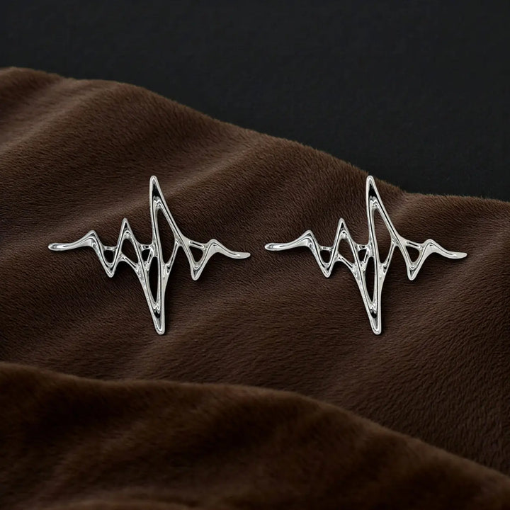 ANI Accessories pair of silver wave design brooches on dark brown fabric 