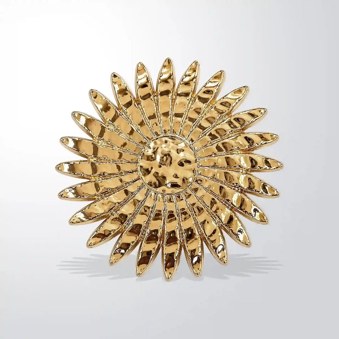 ANI Accessories sun style metal brooch in hammered gold with layered petal rays, on grey 