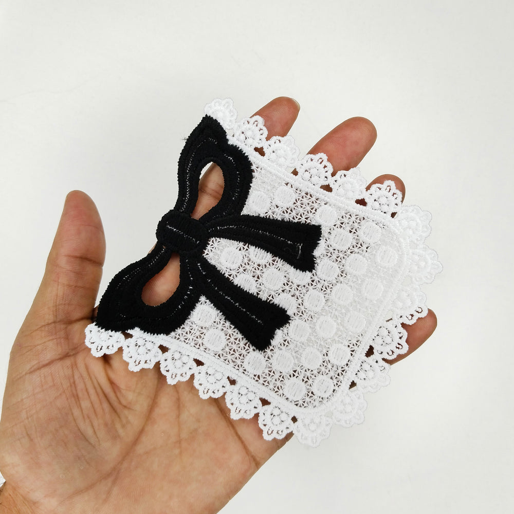 ANI Accessories white pocket patch with black bow held in an open palm to show its size  with white color background 