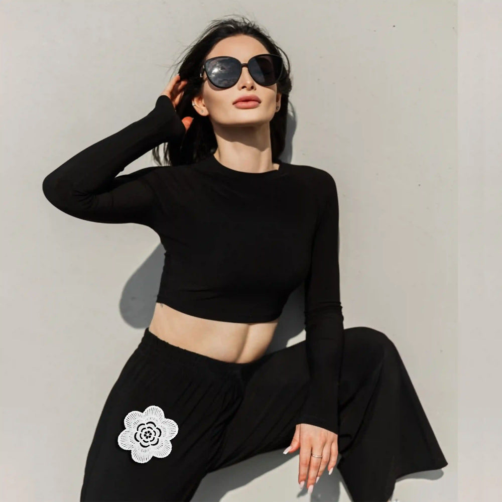 ANI Accessories white flower applique patch on black trousers worn by a seated model 